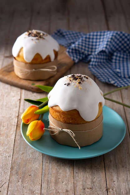 Traditioneller Osterkuchen, bunte Eier und Tulpen auf Holztisch.