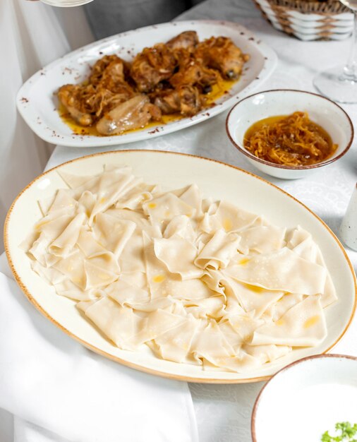 traditionelles blattförmiges Khinkal und ein Teller mit gebratenem Hühnchen mit Zwiebeln