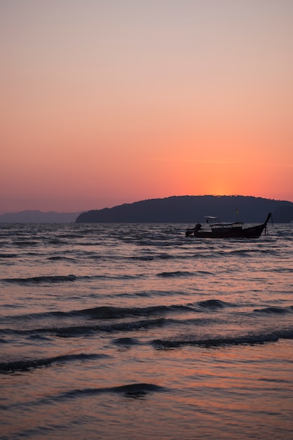 Traditionelles hölzernes thailändisches Passagierboot des langen Schwanzes auf Meer am Abend