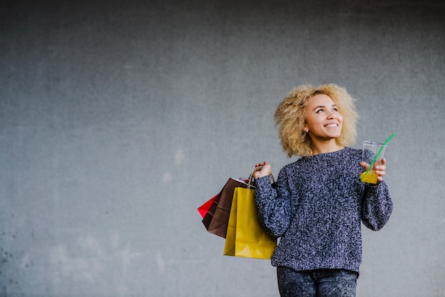 Kostenloses Foto träumerisches mädchen mit getränk und taschen