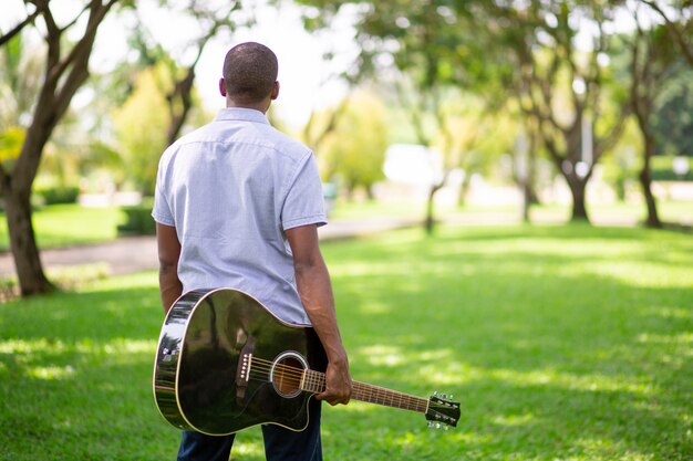 Tragende Gitarre des schwarzen Mannes im Park