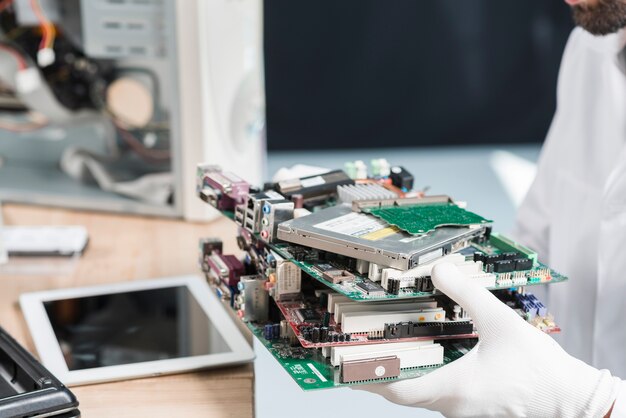 Tragende Handschuhe der männlichen Technikerhand, die Computerteile halten