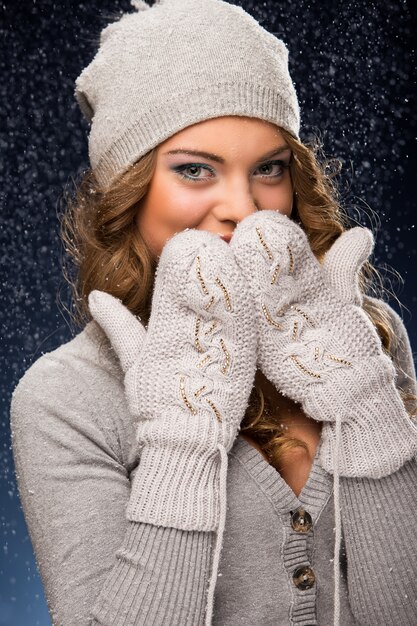 Tragende Handschuhe des netten gelockten Mädchens während der Schneefälle