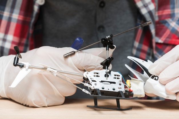 Tragende Handschuhe des Technikers, die Hubschrauberspielzeug reparieren