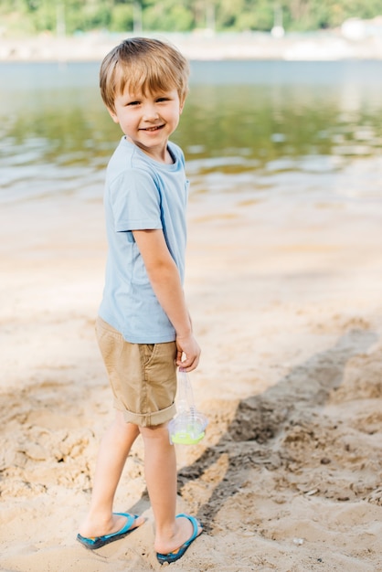 Tragende Schutzbrillen des Jungen drehen sich herum am Strand