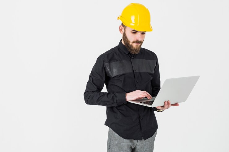Kostenlose Foto tragender hardhat des männlichen ingenieurs, der laptop gegen weißen hintergrund verwendet