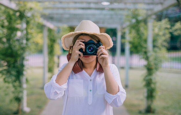 Tragender Hut der jungen Frau, der mit Kamera fotografiert