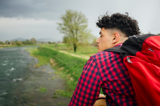 Tragender Rucksack des Mannes, der nahen Fluss steht