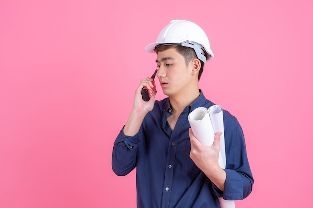 Tragender weißer Sturzhelm des jungen Architektenmannes des Porträts und Griffmegaphon in der Hand