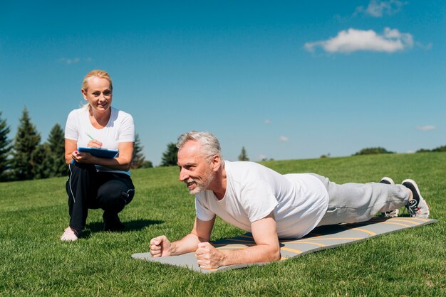 Trainer, der den Plankenwiderstand des Mannes misst