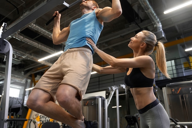 Trainer hilft Anfängern im Fitnessstudio