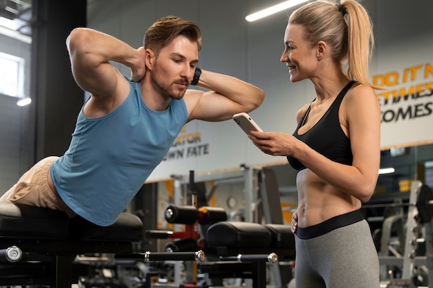 Trainer hilft Anfängern im Fitnessstudio