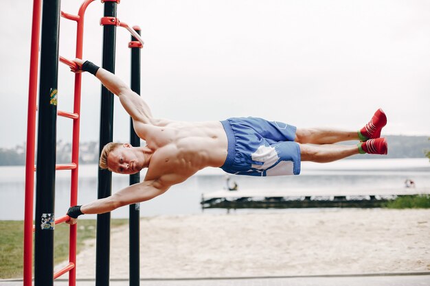 Training des gutaussehenden Mannes in einem Sommerpark