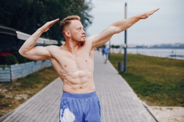 Training des gutaussehenden Mannes in einem Sommerpark