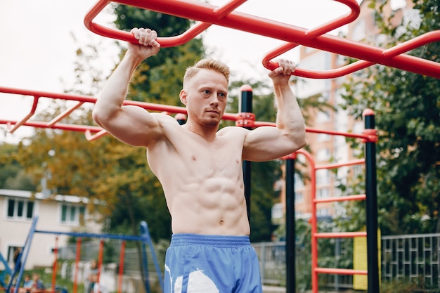 Training des gutaussehenden Mannes in einem Sommerpark