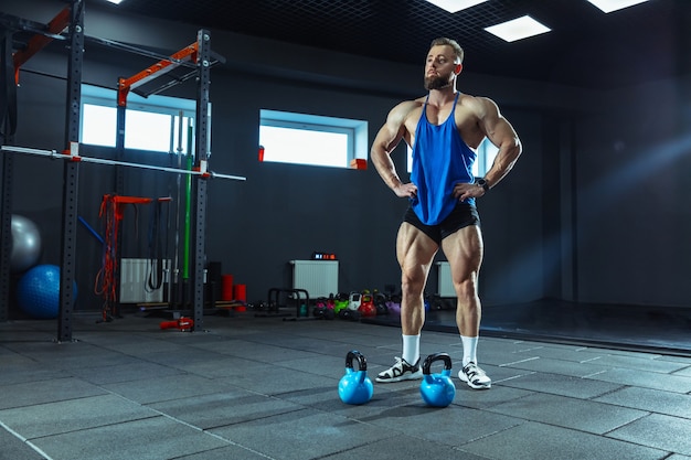 Training des jungen muskulösen Athleten im Fitnessstudio, das Kraftübungen macht