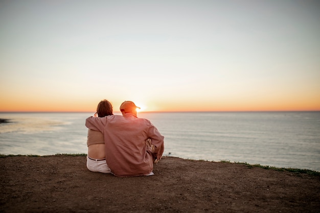 Trans-Paar, das den Sonnenuntergang am Strand beobachtet