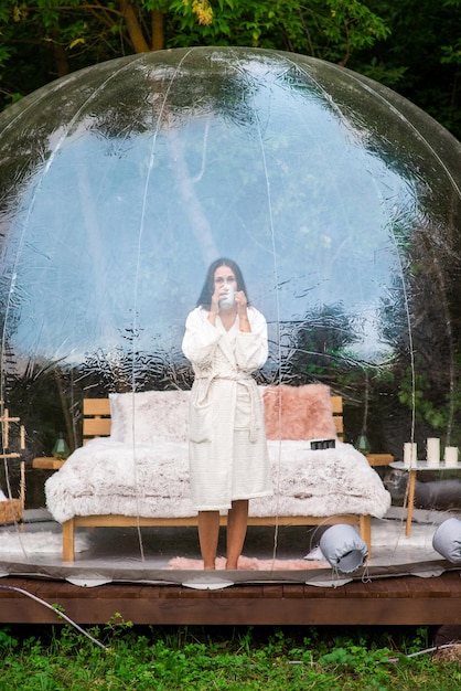 Transparentes Blasenzelt und Frau beim Glamping