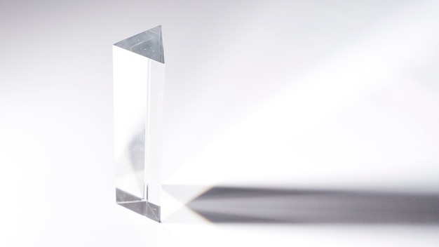 Transparentes Kristallprisma mit dunklem Schatten auf weißem Hintergrund