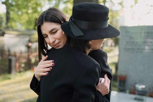 Trauernde Mutter und Tochter an einem Grab auf dem Friedhof