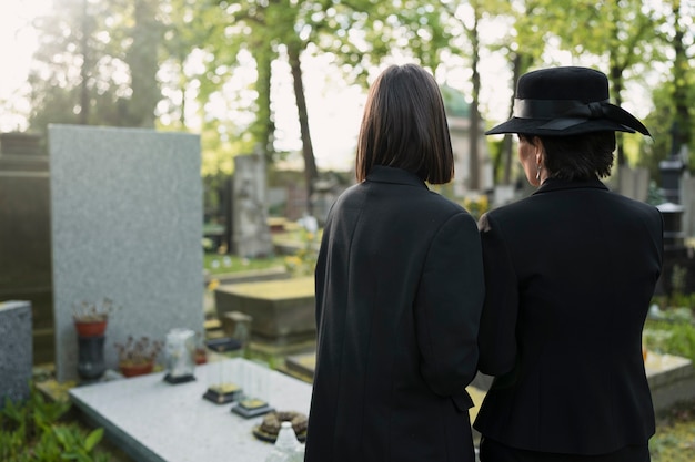 Trauernde Mutter und Tochter an einem Grab auf dem Friedhof