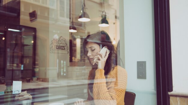 Traurige Frau, die am Telefon im Café spricht