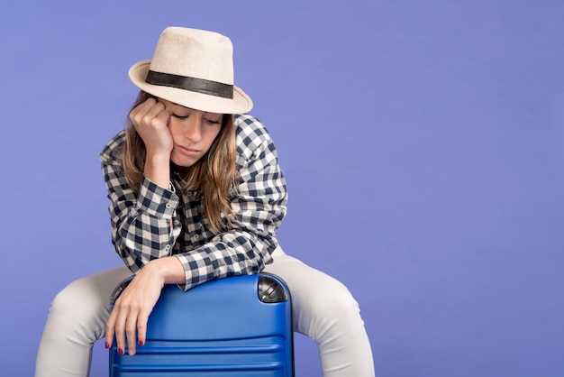 Traurige Frau, die auf Gepäck sitzt