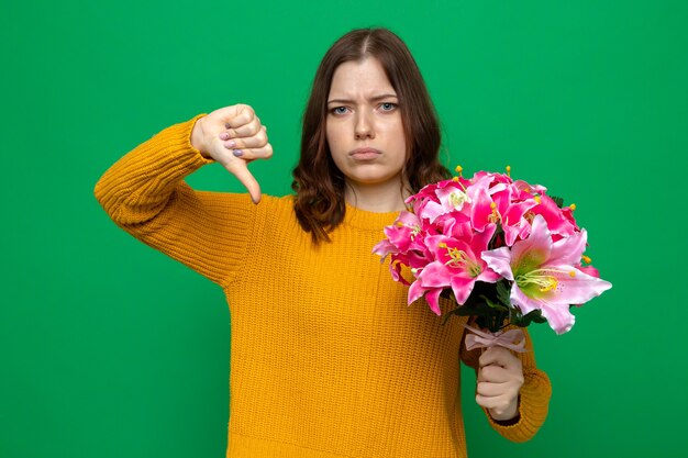 Traurige Frau zeigt Daumen nach unten und hält Blumenstrauß