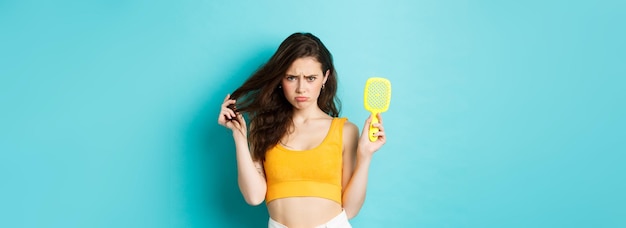 Kostenloses Foto traurige junge frau, die bürste mit strähnen zeigt, die haarausfallproblem haben, braucht kosmetische schönheitsbehandlung s