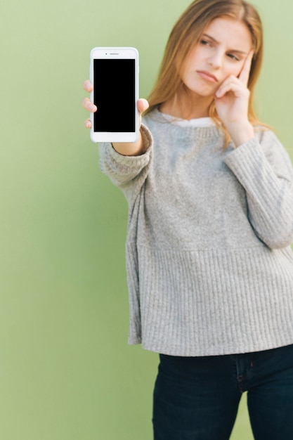 Kostenloses Foto traurige junge frau, die handy in richtung zur kamera zeigt