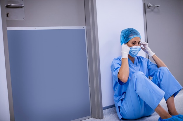 Trauriger chirurg, der auf boden im korridor sitzt