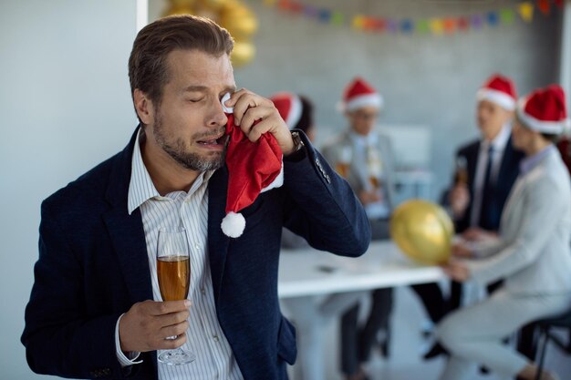 Trauriger Geschäftsmann weint, während er auf der Neujahrsparty im Büro ist