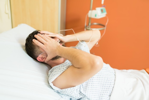 Trauriger unwohler patient, der sich deprimiert fühlt, während er im krankenhaus auf dem bett liegt