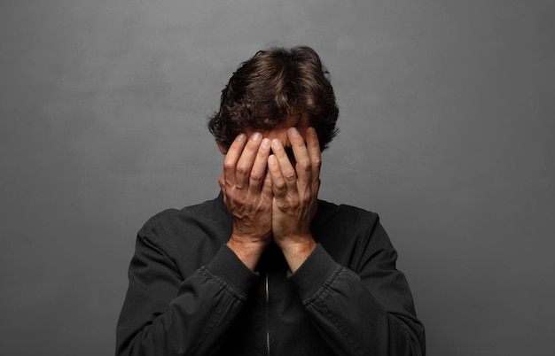 Trauriges Gefühl, frustriert, nervös und deprimiert, das Gesicht mit beiden Händen bedeckt, weinen