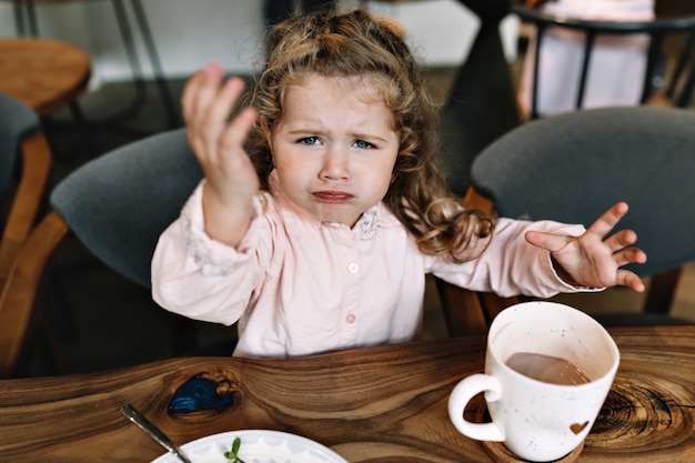 Trauriges kleines Mädchen sitzt an einem Tisch in einem Restaurant