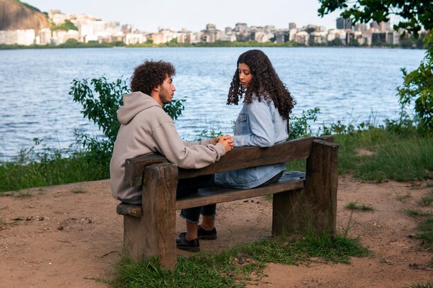 Trauriges Paar sitzt auf der Bank am See