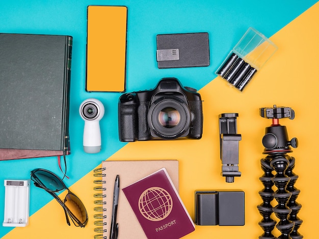 Traveller-Blogger-Kit für den Sommerurlaub. Ansicht von oben. Flach liegen. Kamera mit Zubehör neben Sonnenbrille, Bücher, Smartphone, Notizbuch und Reisepass