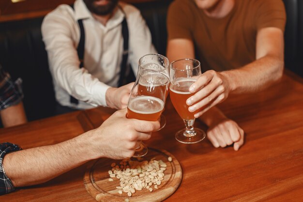 Treffen mit den besten Freunden. Drei glückliche junge Männer in Freizeitkleidung sprechen und trinken Bier, während sie zusammen in der Bar sitzen.