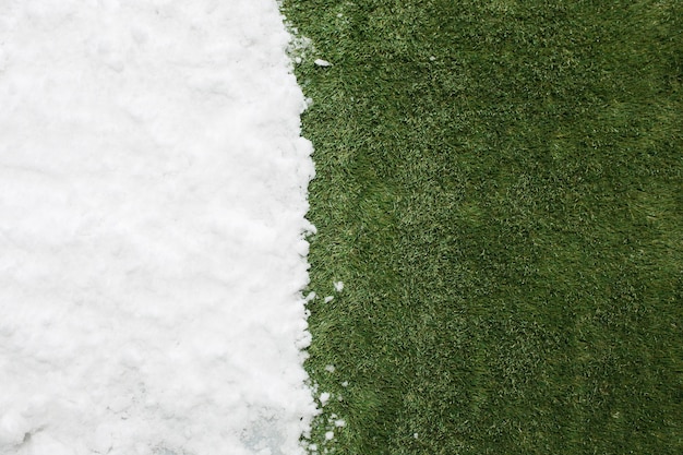 Treffen von weißem Schnee und grünem Gras hautnah. zwischen Winter und Frühling Konzept Hintergrund.