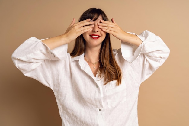 Trendige brünette Frau schließt ihre Augen an ihren Händen und denkt minimalistischen Stil