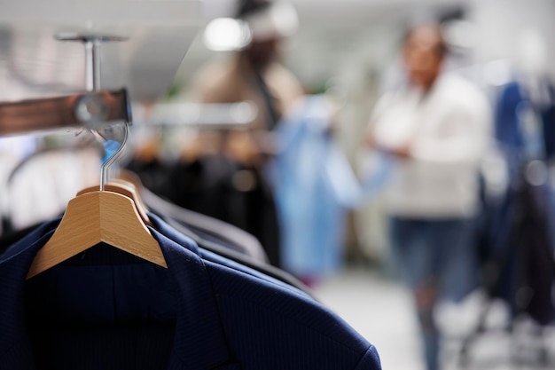 Trendige Jacken auf Kleiderbügeln im Bekleidungsgeschäft mit verschwommenem Hintergrund. Lässige, moderne Blazer aus der neuen Kollektion, die im Einkaufszentrum am Regal hängen, Nahaufnahme, selektiver Fokus