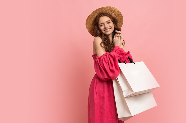 Trendige, stilvolle Frau, die sich über Verkauf, Einkaufszeit freut, einzeln auf rosafarbenem, lässigem Outfit.