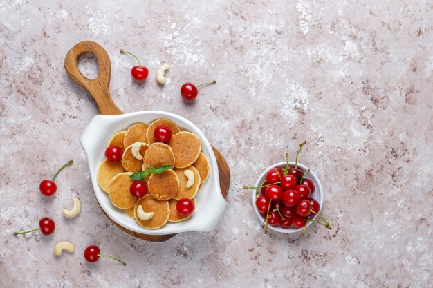 Trendy Food - Mini-Pfannkuchen-Müsli. Haufen Getreidepfannkuchen mit Beeren und Nüssen.