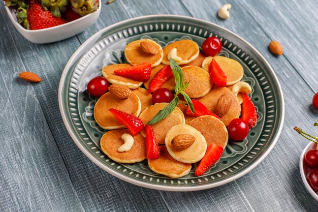 Trendy Food - Mini-Pfannkuchen-Müsli. Haufen Getreidepfannkuchen mit Beeren und Nüssen.