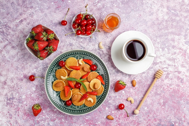 Trendy Food - Mini-Pfannkuchen-Müsli. Haufen Getreidepfannkuchen mit Beeren und Nüssen.