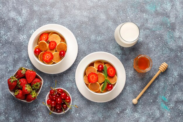 Trendy Food - Mini-Pfannkuchen-Müsli. Haufen Getreidepfannkuchen mit Beeren und Nüssen.