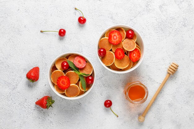 Trendy Food - Mini-Pfannkuchen-Müsli. Haufen Getreidepfannkuchen mit Beeren und Nüssen.