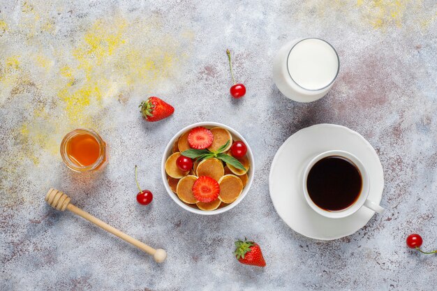 Trendy Food - Mini-Pfannkuchen-Müsli. Haufen Müsli-Pfannkuchen mit Beeren und Nüssen.