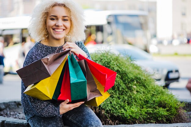 Kostenloses Foto trendy mädchen mit käufe sitzen auf der straße