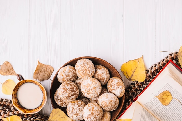 Trinken Sie und Lebkuchen in der Nähe von Buch und Schal